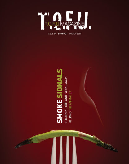 Image contains a dark red background with a silver fork coming up from the bottom of the frame. On the fork, a single piece of asparagus is visible. Both ends of the asparagus are burnt, and the right end has a small stream of smoke coming from it. Above the fork and the asparagus, there are two vertical blocks of text. The larger one on the left says "Smoke Signals". The word "smoke" is in white, and the word "signals" is in green. The smaller block of text says "Is burning out and fading away" in one line and "helping the animals" in another. The words "the animals" are in green. At the very top of the image, there is text that says "T.O.F.U." in white, and within that text there is more text that says "T.O.F.U. Magazine". Just below the white T.O.F.U., there is text that says "Issue 14 Burnout March 2019".